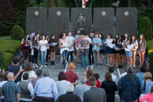 Students from the Westchester Sandbox Theatre, located in Mamaroneck, sing to community members in front of the memorial by the Courtroom in Mamaroneck during the candlelight vigil for the victims of the mass shooting. Photo/Chris Courtney