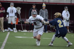 Thomas Gresham fights off a Lourdes defender at Harrison High School on April 1. Gresham had two goals and four assists in the Huskies’ 14-6 win.