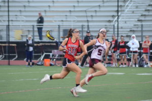 Rye's Leah Kenny rushes past a Harrison defender on May 12. Harrison will play No. 6 seed Suffern in the first round of the Class B playoffs.